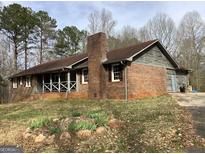 Charming brick home with a cozy screened in porch and a stone chimney at 13370 Panhandle Rd, Hampton, GA 30228