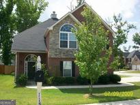 Charming brick home with arched window, manicured lawn, and mature landscaping, offering inviting curb appeal at 11599 Flemmings Cove Dr, Hampton, GA 30228