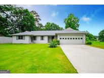 Charming ranch-style home with a well-manicured lawn, a two-car garage, and gray trim at 65 Pine Haven Ct, Carrollton, GA 30116
