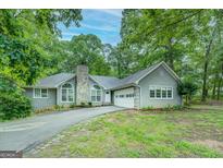 Charming single-story home with a stone chimney, attached garage, and a beautifully landscaped front yard at 2690 Ross Rd, Snellville, GA 30039