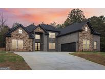 Stunning two-story home boasts a stone and brick facade, a sprawling driveway, and a lush, landscaped lawn at 4186 Matisse Ln, Fairburn, GA 30213