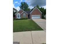 Charming single-Gathering home featuring a well-manicured lawn and a two-car garage at 1925 Cedar Walk Ln, Conley, GA 30288