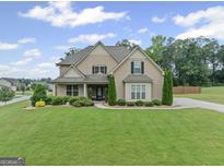 Charming two-story home with a well-manicured lawn and lush landscaping at 108 Donovan Ave, Locust Grove, GA 30248
