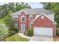 Two-story brick home featuring a well-manicured lawn and a light blue front door, inviting entrance and attached garage at 2600 Neighborhood Walk, Villa Rica, GA 30180