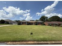 Charming brick home with manicured lawn and tidy landscaping under a partly cloudy blue sky at 410 Clubland Se Cir, Conyers, GA 30094