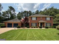 Charming brick home featuring a two-car garage, manicured lawn, and traditional design with blue shutters at 404 Windsor Way, Peachtree City, GA 30269