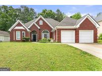 Charming red brick home features a two-car garage and a well-manicured front lawn at 3955 Sweetwater Pkwy, Ellenwood, GA 30294