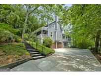 Beautiful two-story home featuring a 2-car garage, wood siding, stone chimney and stairs leading to the front porch at 610 Lake Dr, Snellville, GA 30039