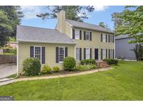 Traditional two-story home with lush landscaping and a classic black front door and shuttered windows at 557 Spring Creek Ne Way, Marietta, GA 30068