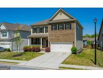 Charming two-story home with a brick and siding exterior, attached two-car garage, and well-maintained front lawn at 2649 Ogden Trl, Buford, GA 30519