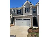 Charming townhome featuring a two-car garage, brick accents, and stylish gray siding at 1402 Grand Branch Dr, Lawrenceville, GA 30045