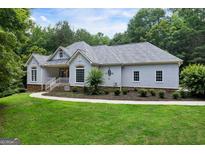 Charming stucco home with manicured lawn, showcasing a blend of modern design and classic appeal at 1460 Bakers Bridge Rd, Douglasville, GA 30134