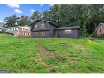 Charming two-story home with a black brick exterior and lush green lawn at 1239 Teakwood Trl, Stone Mountain, GA 30083