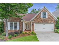 Charming stone front exterior with well-manicured lawn and attached two-car garage with bright white doors and trim at 370 Grand Teton Cir, Fayetteville, GA 30215