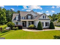 Eye-catching two-story home showcasing stone accents, dark shutters, professional landscaping, and lush green lawn at 55 Jolie Ln, Sharpsburg, GA 30277