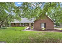 Beautiful brick home with a well manicured lawn and black shutters on a partially cloudy day at 190 Willow Lake Ln, Sharpsburg, GA 30277