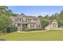 Charming two-story home featuring a manicured lawn, stone accents, and a detached garage at 2975 Hickory Hill Rd, Brooks, GA 30205