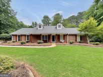 Charming brick home with a well-manicured lawn, dormer windows, and inviting front porch swing at 602 Pine Knoll Court, Mcdonough, GA 30252
