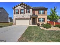 Two-story home featuring brick accents, vinyl siding, a two-car garage, and landscaped front yard at 237 Cranapple Ln, Mcdonough, GA 30253