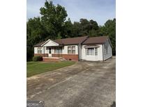 Charming single-story home with gray siding, brick accents, and a spacious concrete driveway at 5225 Silhouette Sw Ln, Mableton, GA 30126