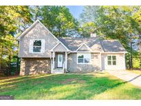 Charming two-story home with stone accents, gray siding, a manicured lawn, and inviting curb appeal at 8500 Bowen Ct, Jonesboro, GA 30238