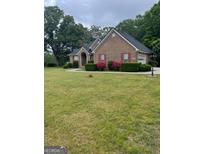 Well-maintained brick home with a spacious front yard and blooming shrubs at 2142 E Atlanta Rd, Stockbridge, GA 30281
