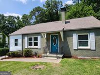 Charming single-story home featuring a blue front door, shutters, and a well-maintained lawn and landscaping at 615 Cofield Dr, Hapeville, GA 30354