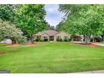 Inviting home featuring a well-manicured lawn, mature trees, and charming curb appeal at 55 Ashton Pl, Covington, GA 30016