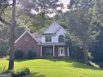 Charming two-story brick home with a well-manicured front lawn and lush landscaping at 90 Barrington Grange Dr, Sharpsburg, GA 30277