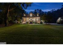 Elegant two-story home with a large front porch, brick accents, and lush landscaping at twilight at 654 Cannon Rd, Sharpsburg, GA 30277