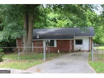 Quaint brick home with a chain-link fence and mature trees shading the front yard at 8469 Shiloh Ct, Jonesboro, GA 30238