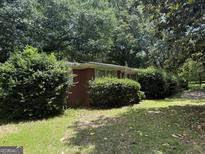 Quaint brick home featuring mature trees, and manicured bushes at 1810 Highway 138 E, Stockbridge, GA 30281