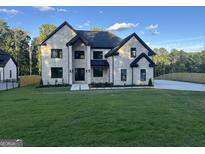 Beautiful white brick home featuring black trim, a well manicured lawn, and a contemporary design at 1291 E M Croy Rd, Sugar Hill, GA 30518