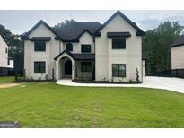 Stunning new construction home features a white brick facade, black trim, and professionally landscaped yard at 1293 E M Croy Rd, Sugar Hill, GA 30518
