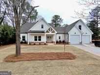 Charming two-story white home with an attached two-car garage and a beautifully landscaped front yard at 6149 Pinewood Se Dr, Covington, GA 30014