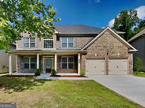 Charming two-story brick home with a well-manicured lawn, covered porch, and two-car garage at 3507 Hideaway Ln, Loganville, GA 30052
