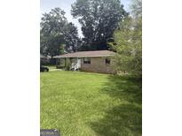 Charming brick ranch home with a lush green lawn and mature trees at 341 Boxwood St, Social Circle, GA 30025