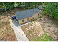 Aerial view of a single-story brick home with a gray roof and a concrete driveway surrounded by trees at 6010 Fieldcrest Dr, Morrow, GA 30260