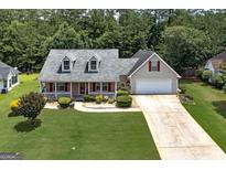 Inviting home featuring a charming front porch, well-manicured lawn, and a convenient two-car garage at 35 Deep Springs Way, Covington, GA 30016