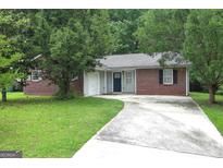 Charming brick home featuring a paved driveway, lush lawn and mature shade trees enhancing curb appeal at 2039 Faith Cv, Atlanta, GA 30349