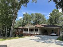 Inviting single-story home with a covered porch and a spacious carport nestled among lush trees at 370 Rosetta Nw Ln, Conyers, GA 30012