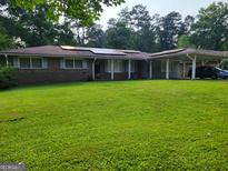Charming brick home with a well-maintained lawn, solar panels, and a convenient carport at 4157 Cedar Valley Ln, Conley, GA 30288