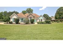 Inviting single-story home with manicured lawn, stone accents, and charming teal shutters at 115 Sunderland Cir, Fayetteville, GA 30215
