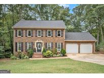 Charming brick home with a well-manicured front yard, black shutters, and a two-car garage at 1911 Geyser Trce, Lawrenceville, GA 30044
