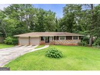 Charming home featuring a stone accent wall, two-car garage, and well-maintained front yard at 115 Club Cir, Stockbridge, GA 30281