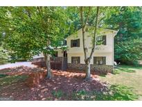 Charming two-story home with a stone foundation and a spacious deck, surrounded by lush trees at 2031 Dennis Pl, Buford, GA 30519