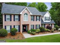 Two-story brick home with dark shutters and a well-manicured lawn and garden at 1120 Upchurch Rd, Mcdonough, GA 30252