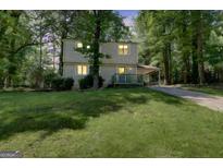 Two-story home with vinyl siding, a carport, and a well-maintained front lawn surrounded by mature trees at 405 Abbey Rd, Peachtree City, GA 30269