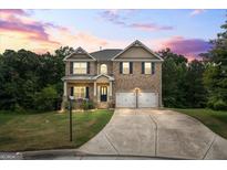 Charming two-story brick home with a well-manicured lawn and a two-car garage under a beautiful sunset at 1492 Bourdon Bell Drive Se, Conyers, GA 30013