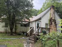 Exterior front of property featuring a small porch, overgrown foliage, and a chimney at 11591 Turner Rd, Hampton, GA 30228